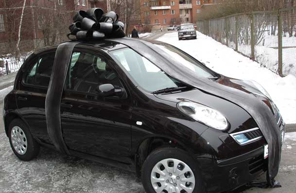 автомобиль Ниссан Микра черного цвета с бантом на крыше в цвет автомобиля